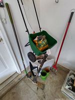 Photo of green broadcast spreader loaded with gardening tools and pots, also showing Toro grass catcher bag and garden tools nearby