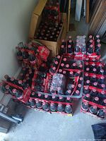 Large collection of unopened Coca-Cola glass bottles in original cardboard carriers and loose bottles stacked on floor, mostly Nascar collectible designs.