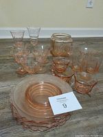 Full view of the 22-piece pink depression glass set including plates, bowls, stemmed glasses, and a jar.