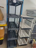 Full view of gray and white plastic shelving units standing side by side showing size difference and condition.