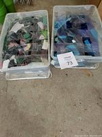 Two bins placed side by side on the floor, one with mixed color stained glass scraps and the other with blue stained glass scraps.