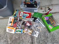 Various boxed model train kits and track components with loose small parts and figures