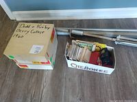 Boxes of Viewmaster slides, Kodak slide carousels, and projector screen tripod stand shown on floor.