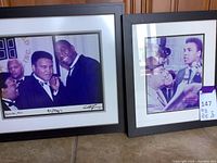 Photo showing both framed signed prints of Muhammad Ali and Magic Johnson, side by side on floor.