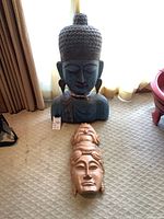 Two Buddha art pieces on carpet, large blue carved bust and wooden mask