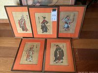 Overview of five framed burlap art prints on wooden floor.