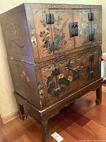 Front view of assembled cabinet showing painted floral and bird panels