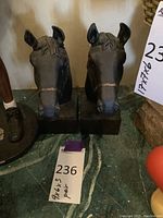 Front view of two metal horse head bookends on square bases, showing straight-on view of faces.