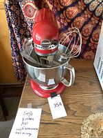 Front view showing red mixer with bowl and whisk on wooden surface