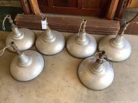 Six silver-painted metal dome light fixtures arranged on concrete floor, view showing overall quantity and design