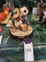 Full view of colorful Mickey Mouse hugging Pluto statue on a round base with plaque.