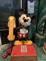 Front view of vintage Mickey Mouse telephone showing figure, handset, keypad, and coiled cord.