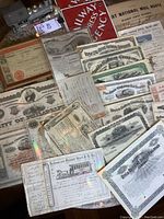 Overhead view of assortment of railroad stock certificates and bond documents on table