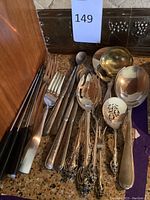 Assorted flatware and serving utensils grouped on countertop