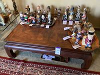 Front and top view of low wooden coffee table showing incised wood surface and brass corner hardware, surrounded by various figurines (not included).