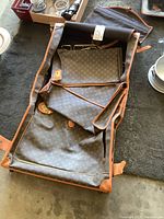 Open garment bag showing interior lining and monogram canvas exterior.