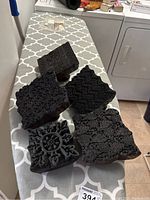 Five antique carved wood printing stamps arranged on patterned ironing board showing diverse floral and geometric patterns on block surfaces.
