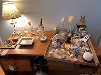 Wide view of table with assorted bottles, vases, ceramic buildings, and figurines.
