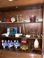 Full view of shelf showing ceramic bird candle holders, brass candle holders, trinket boxes, owl figurine, souvenir blocks, and mini bowls.