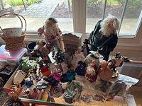 Wide shot showing the variety of Santa Clauses, Victorian and Dutch figurines, miniature furniture and ornaments arranged on table.