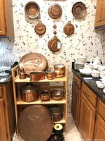 Overall corner view showing wall-mounted copper molds and wooden shelf with cookware