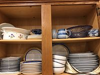 Upper shelves showing a variety of Dansk china including bowls, plates, and an art glass bowl with blue and brown swirl design