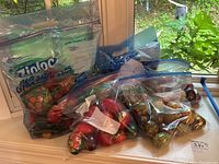 Various painted eggs including Russian eggs, solid and hollow wooden eggs, some opening wooden eggs, stored in Ziplock bags on a windowsill.