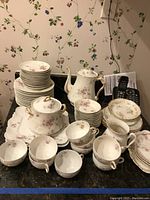 Full view of most set pieces including cups, saucers, serving platters, coffee pot, creamer, sugar bowl and stacked plates