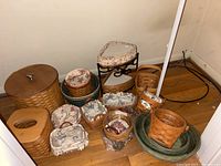 Collection of various Longaberger woven baskets, some with floral fabric liners, a large basket with wooden lid, and a mini shelf