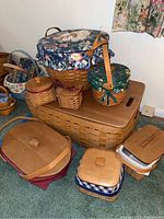 Full grouping of Longaberger baskets in various sizes with fabric covers and wooden lids on floor and table