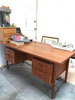Full front and left side view of teak desk showing top surface, left pedestal and tapered leg
