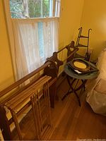 Photo shows two wooden quilt racks with heart cutouts, folding wooden drying rack, black metal shelf, small glass shelf unit, and unopened glass shelf