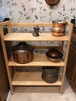 Front view of the wooden rolling shelf with copper and metal kitchenware on shelves, displaying the structure and size.
