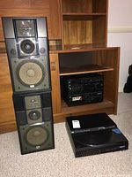 Two Sansui S-M90 bookshelf speakers stacked showing multiple drivers behind grille and black cabinets.