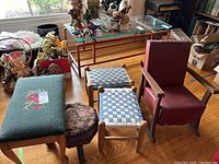 Wide view showing large needlepoint foot stool, two woven stools, smaller needlepoint foot stool, and child's rocking chair among other items in room.