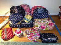 All Vera Bradley quilted fabric zipper bags arranged on floor in various patterns and colors