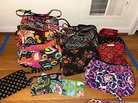 Full arrangement of 10 Vera Bradley quilted bags and zippered pouches arranged on wooden floor.