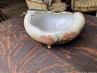 View of the hand-painted Art Nouveau porcelain bowl showing off the scalloped gold-trimmed rim, soft painted oak leaves and acorns design, and rounded feet.