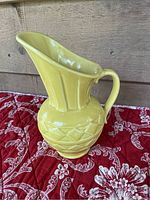 Front right angle view of yellow ceramic McCoy pitcher showing wide spout, handle, and geometric pattern.