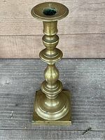 Full view of the English brass candlestick showing the shaped stem and round candle socket.