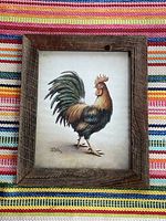 Framed rooster print with rustic handmade pine frame on multicolored woven fabric background.