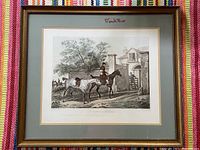 Frontal photo of the framed French equestrian print showing the horseman riding a horse and leading another horse with a saddle, with architectural and natural background elements.