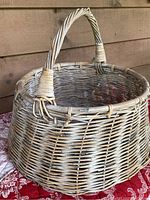 Side view of the large vintage wicker basket showing woven wicker construction and handle.