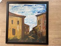 Full view of impressionist oil painting of Italian village buildings in a black frame behind glass, 33 inches square.