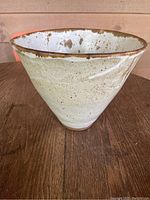 Overall view of the unusual tapered ceramic bowl by A. Stuart showing the shape, glaze, and size relative to the table