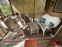 Full view of white wicker furniture set on porch, loveseat, two armchairs, coffee table visible