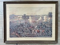 Full view of the framed print depicting the Battle of Gettysburg with visible smoke, soldiers and cannon fire, showing the overall condition and framing.
