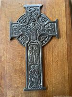 Full view of bronze Celtic cross showing overall shape and carved relief detail.