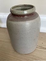 Front view of the pottery jar showing cylindrical stoneware body and reddish-brown drip glaze around the top.