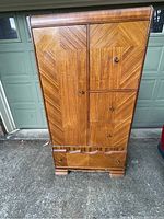 Front view showing geometric mahogany veneer paneling, left closet door, right hat box door, and two drawers below